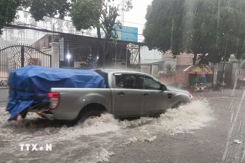 Xe cộ di chuyển khó khăn tại điểm ngập trên đường Cách Mạng Tháng Tám, giáp ranh giữa thành phố Thủ Dầu Một và thành phố Thuận An, tỉnh Bình Dương. (Ảnh: TTXVN phát)