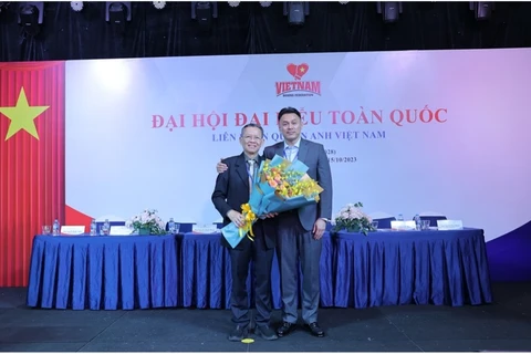 Tân Chủ tịch Liên đoàn Quyền anh Việt Nam Lưu Tú Bảo (phải) trao hoa cho Chủ tịch tiền nhiệm Trần Minh Tiến. (Ảnh: PV/Vietnam+)