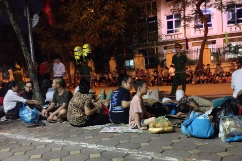 Hàng trăm người đợi diễu binh trong giấc ngủ chập chờn trên vỉa hè. (Ảnh: PV/Vietnam+)