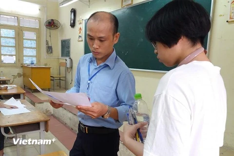 Tại điểm trường THPT Việt Đức, thí sinh đã tập trung từ sáng sớm. Các thí sinh được giám thị hướng dẫn chi tiết cách ghi các thông tin trên giấy nháp và giấy báo dự thi. (Ảnh: Phạm Mai/Vietnam+) 