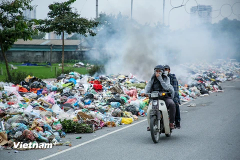Người dân đi qua khu vực bãi rác lộ thiên này tỏ ra vô cùng khó chịu (Ảnh: Minh Sơn/Vietnam+) 