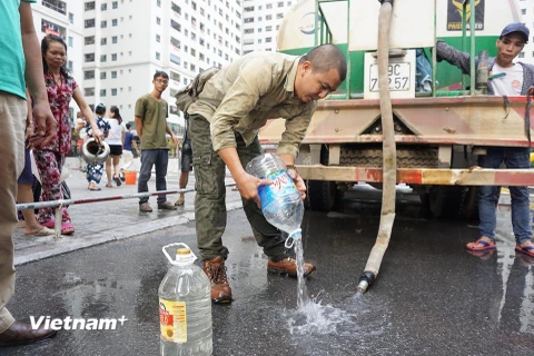 Hứng nước sạch rồi lại phải đổ đi vì nước có mùi tanh khó chịu. (Ảnh: PV/Vietnam+) 