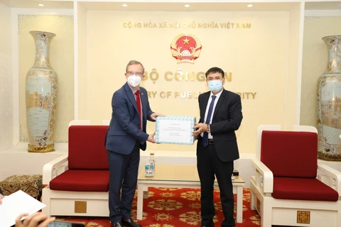 Trung tướng Trương Văn Thông, Cục trưởng Cục Đối ngoại trao khẩu trang của Bộ Công an Việt Nam gửi tặng các cơ quan thực thi pháp luật Anh cho Đại sứ Anh tại Việt Nam Gareth Ward. (Ảnh: Bộ Công an) 