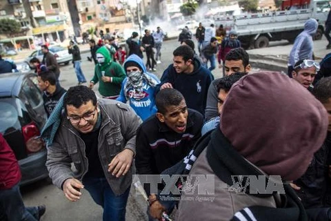 Người biểu tình chạy tránh đạn hơi cay của cảnh sát trong cuộc xung đột ở thủ đô Cairo ngày 17/1. (Ảnh: THX/TTXVN)