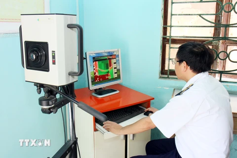Cán bộ Trung tâm Kiểm dịch Y tế Quốc tế Lạng Sơn kiểm tra thân nhiệt của khách nhập cảnh qua máy soi tại Cửa khẩu Tân Thanh. (Ảnh: Thái Thuần/TTXVN)