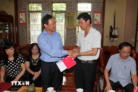 Phó Tổng Giám đốc Lê Duy Truyền trao sổ tiết kiệm cho thân nhân liệt sỹ Lê Duy Quế. (Ảnh: Thanh Tùng/TTXVN)