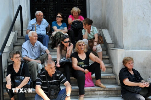 Người được hưởng trợ cấp và lĩnh lương hưu xếp hàng chờ đợi bên ngoài trụ sở Ngân hàng quốc gia Hy Lạp đã đóng cửa ở Thessaloniki. (Nguồn: AFP/TTXVN)