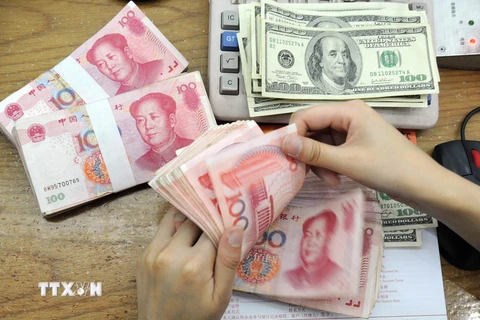Kiểm tiền nhân dân tệ và USD tại ngân hàng ở tỉnh An Huy, Trung Quốc. (Nguồn: AFP/TTXVN)