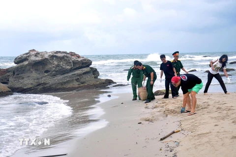 Lực lượng vũ trang và khách du lịch dọn vệ sinh tại khu vực bãi biển Dinh Cậu. (Ảnh: Lê Sen/TTXVN)