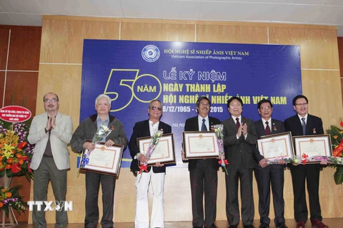 Thứ trưởng Bộ Văn hóa, Thể thao và Du lịch Vương Duy Biên trao kỷ niệm chương vì sự nghiệp Văn học Nghệ thuật cho các nghệ sỹ nhiếp ảnh. (Ảnh: Minh Đức/TTXVN)