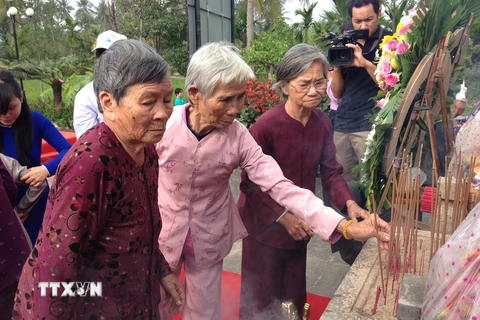 Thân nhân các nạn nhân bị thảm sát thắp hương tưởng niệm tại buổi lễ. (Ảnh: Đinh Thị Hương/TTXVN)