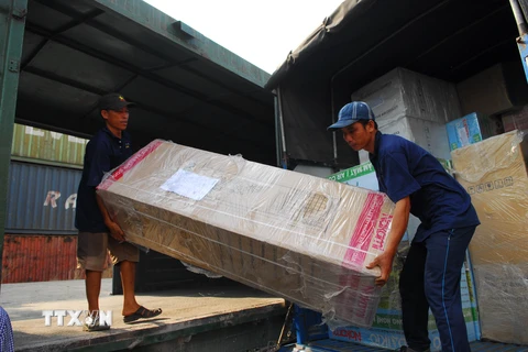 Công nhân bốc dỡ hàng hóa từ trong các toa hàng tại ga Sóng Thần chuyển lên xe tải để đưa đi. (Ảnh: Mạnh Linh/TTXVN)