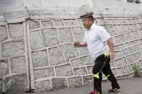 Ông Cong Yan đi bộ trên đường phố với một khối ximăng trên đầu. (Nguồn: shanghaiist.com)