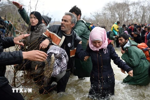 Người di cư và tị nạn cố gắng vượt sông qua khu vực biên giới Hy Lạp-Macedonia để tới Macedonia ngày 14/3/2016. (Nguồn: AFP/TTXVN)
