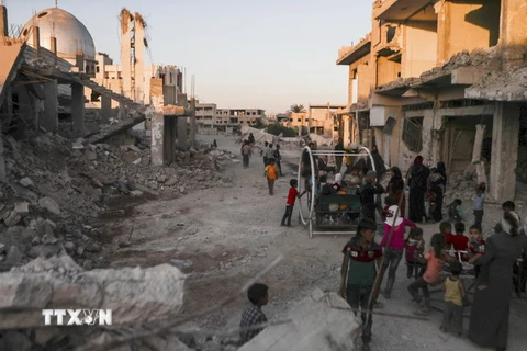 Trẻ em Syria chơi đùa bên cạnh những ngôi nhà đổ nát tại khu vực ngoại ô Al-Nashabiyah, ngày 26/6. (nguồn: AFP/TTXVN)
