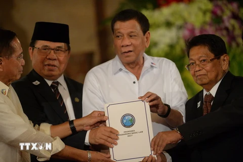 Tổng thống Rodrigo Duterte (giữa) và đại diện của MILF giơ cao dự luật mang tên “Luật Cơ bản Bangsamoro” tại buổi lễ ở Manila. (Nguồn: AFP/TTXVN)
