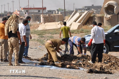 Người dân Iraq đưa xác các nạn nhân lên khỏi một hố chôn tập thể. (Nguồn: AFP/TTXVN)