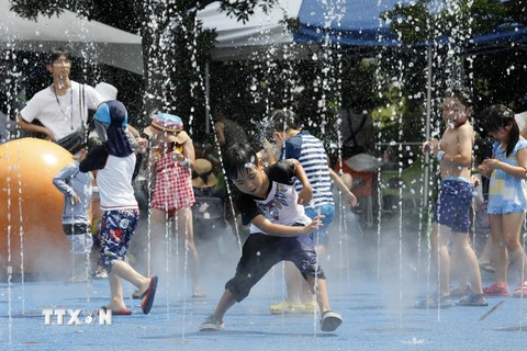 Trẻ em chơi đùa dưới vòi phun nước để tránh nắng nóng tại Tokyo, Nhật Bản ngày 9/8. (Nguồn: EPA/TTXVN)