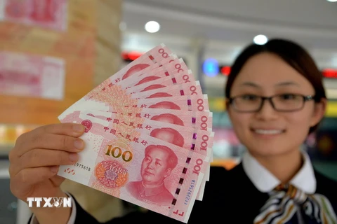 Nhân viên ngân hàng Trung Quốc giới thiệu đồng 100 nhân dân tệ thiết kế mới tại Handan, tỉnh Hà Bắc. (Nguồn: AFP/TTXVN)