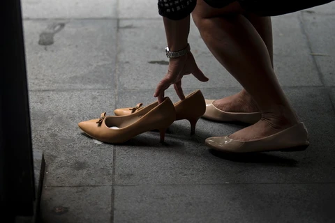 Một nữ nhân viên công sở Philippines thay giày cao gót khi hết giờ làm tại Makati ngày 25/9. (Nguồn: AFP/TTXVN)