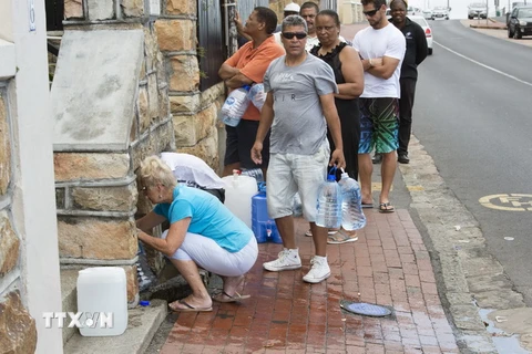 Người dân xếp hàng lấy nước từ mạch nước ngầm ở St. James, Cape Town, Nam Phi. (Nguồn: AFP/TTXVN)
