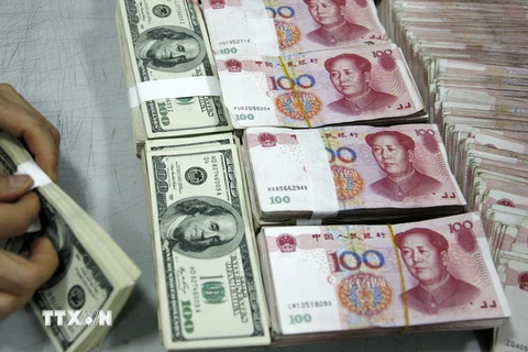 Kiểm tiền nhân dân tệ (phải) và đồng USD (trái) tại ngân hàng ở tỉnh An Huy, Trung Quốc. (Nguồn: AFP/TTXVN)