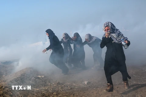 Người biểu tình Palestine chạy trốn khỏi khu vực hơi cay trong cuộc xung đột với binh lính Israel tại biên giới Gaza-Israel ngày 15/5. (Nguồn: EPA/TTXVN)