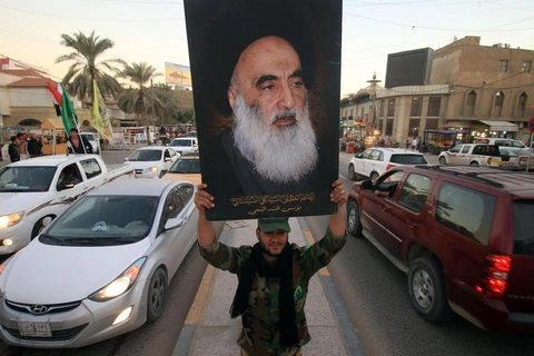 Một thành viên của Hashed al-Shaabi cầm ảnh chân dung của Đại giáo chủ Ali al-Sistani. (Nguồn: AFP)