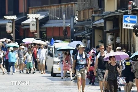 Người dân che ô tránh nắng tại Kyoto, Nhật Bản ngày 19/7. (Ảnh: Kyodo/TTXVN)