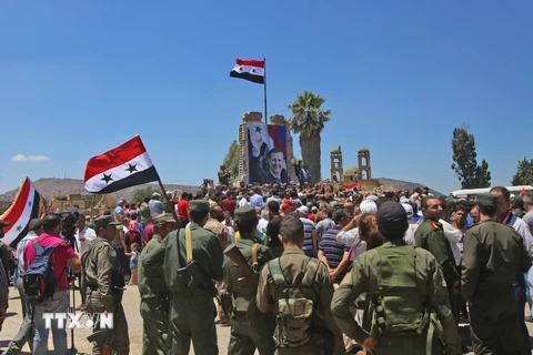 Binh sỹ quân đội chính phủ Syria giương cao quốc kỳ sau khi giải phóng thành phố Quneitra ngày 27/7. (Ảnh: AFP/TTXVN)