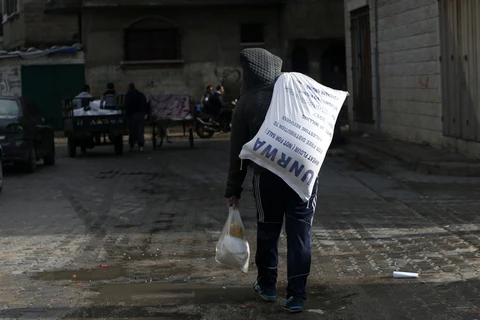  Người dân Palestine chuyển lương thực cứu trợ bên ngoài trung tâm phân phối lương thực của Liên hợp quốc tại Gaza ngày 15/1. (Nguồn: AFP/TTXVN)