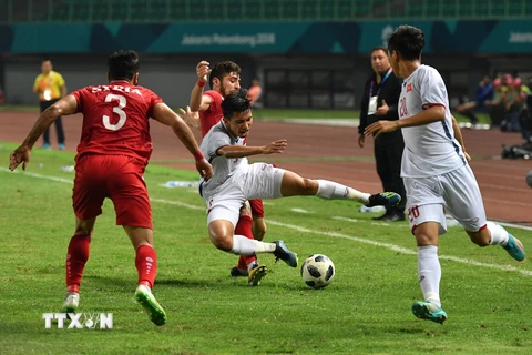 Pha tranh bóng giữa Đoàn Văn Hậu (giữa) với các cầu thủ Olympic Syria ngày 27/8. (Ảnh: TTXVN phát)