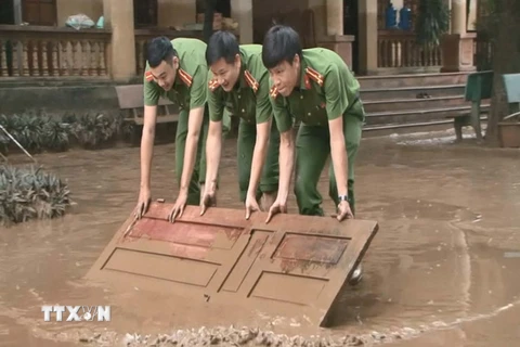 Hơn 100 cán bộ chiến sỹ công an được huy động giúp trường học dọn dẹp bùn đất. (Ảnh: Khiếu Tư/TTXVN)