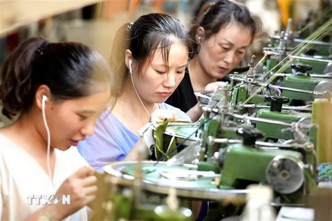 Công nhân làm việc tại một dây chuyền may quần áo xuất khẩu ở tỉnh Hà Nam, Trung Quốc. (Ảnh: AFP/TTXVN)