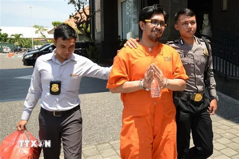 Cảnh sát Malaysia áp giải một tội phạm tại Denpasar ngày 4/10. (Ảnh: AFP/TTXVN)