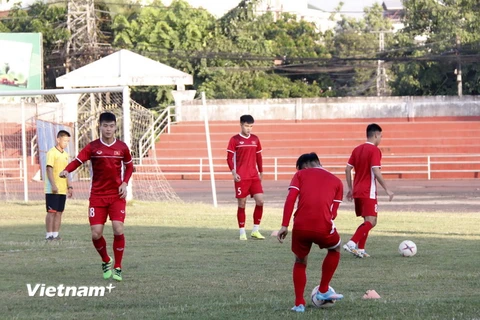 Các cầu thủ đang tập ban chuyền bóng nhẹ nhành trên sân để làm quen với sân và thời tiết tại Lào. (Ảnh: Phạm Kiên/Vietnam+)