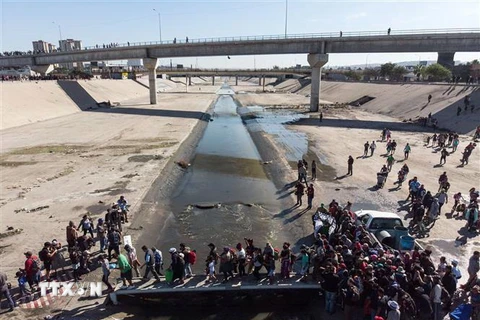 Người di cư Trung Mỹ vượt đoạn sông Tijuana để tới cửa khẩu El Chaparral, gần biên giới Mỹ-Mexico. (Ảnh: AFP/TTXVN)