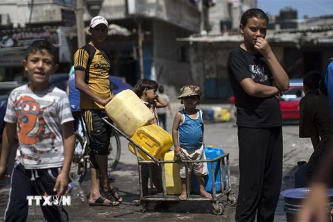 Người dân Palestine xếp hàng lấy nước sinh hoạt tại một trại tị nạn ở Dải Gaza. (Ảnh: AFP/TTXVN)