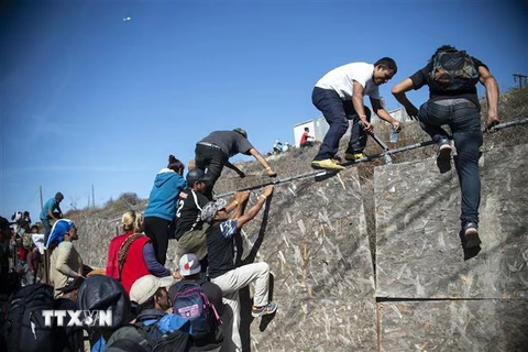 Người di cư Trung Mỹ vượt qua hàng rào biên giới Mỹ-Mexico ở Tijuana, bang Baja California, Mexico tháng 11/2018. (Ảnh: AFP/TTXVN)