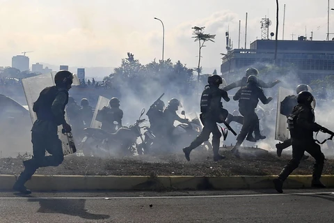 Lực lượng trung thành với Tổng thống Venezuela Nicolas Maduro ngăn các tay súng thuộc nhóm binh sĩ ủng hộ thủ lĩnh đối lập Juan Guaido nổi dậy tại căn cứ quân sự La Carlota ở Caracas ngày 30/4/2019. (Ảnh: AFP/TTXVN)