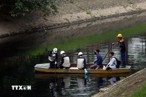 Công nhân đang kiểm tra đoạn sông Tô Lịch nơi đặt máy xử lý ô nhiễm. (Ảnh: Huy Hùng/TTXVN)
