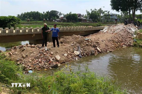 Người dân đổ đất lấp ngang đoạn kênh qua địa bàn thôn Điền Chánh Trung. (Ảnh: Phước Ngọc/TTXVN)