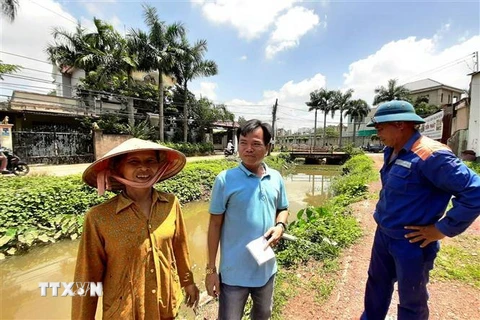 Anh Trung Kiên con trai bà Nguyễn Thị Hoa ( áo xanh ở giữa) trao đổi về việc mẹ hiến căn nhà và đất cho chính quyền cải tạo suối Đồng Tiền. (Ảnh: Dương Chí Tưởng/TTXVN)