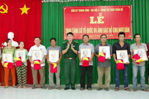 Lãnh đạo bộ đội biên phòng Sóc Trăng trao tặng cờ và ảnh bác Hồ cho ngư dân vùng ven biển Sóc Trăng. (Ảnh: Trung Hiếu-TTXVN)