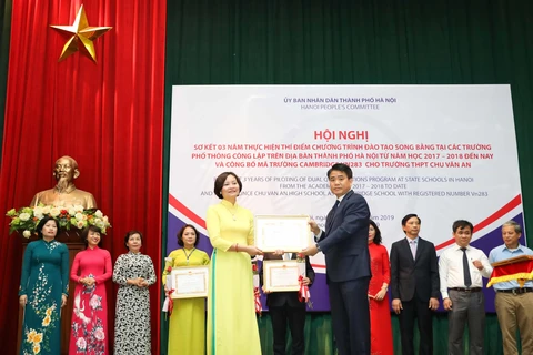 Chủ tịch Ủy ban Nhân dân thành phố Hà Nội Nguyễn Đức Chung tặng Bằng khen cho các tập thể có thành tích trong thực hiện thí điểm chương trình đào tạo song bằng. (Ảnh: Thanh Tùng/TTXVN)
