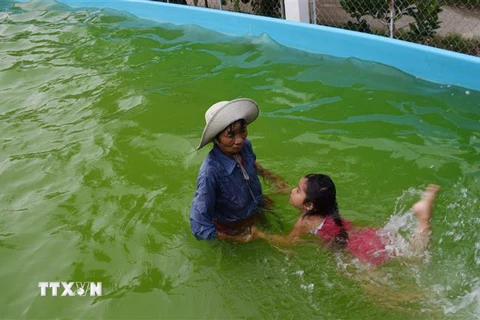 Bà Trần Thị Kim Thia dạy bơi cho trẻ em. (Ảnh: Chương Đài/TTXVN)