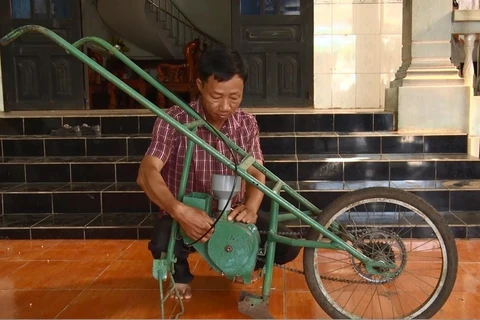 Anh Nguyễn Văn Anh với chế chiếc máy gieo hạt và bón phân. (Ảnh: Lê Xuân/TTXVN)