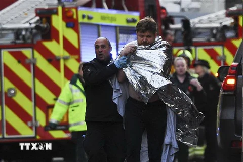 Cảnh sát Anh hỗ trợ một nạn nhân bị thương trong vụ tấn công bằng dao trên cầu London ở thủ đô, tối 29/11/2019. (Ảnh: AFP/TTXVN)