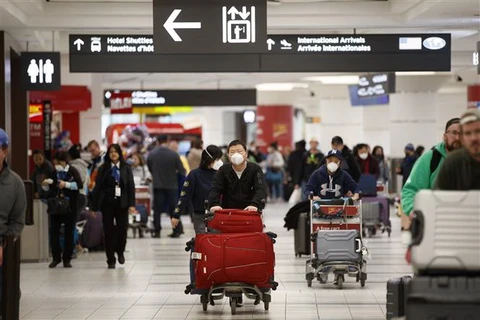 Hành khách đeo khẩu trang đề phòng lây nhiễm virus corona tại sân bay quốc tế Toronto Pearson, Canada. (Ảnh: AFP/TTXVN)