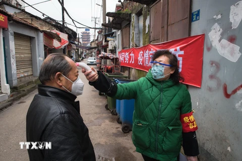Kiểm tra thân nhiệt của người dân nhằm ngăn chặn sự lây lan của COVID-19 tại Vũ Hán, tỉnh Hồ Bắc, Trung Quốc. (Ảnh: THX/TTXVN)